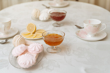 fruit jam, lemon, and sweet meringue for tea on the kitchen table. beautiful breakfast on a white tablecloth