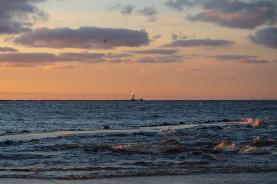 View to the Daugava river falling into the Baltic sea. Colorful sunset sky.  Daugavgriva lighthouse on the horizon. 