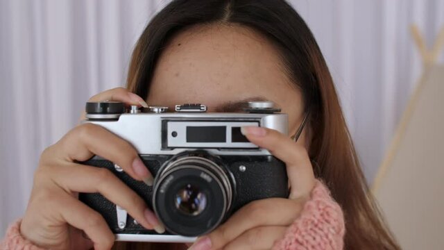 Close up of Middle Eastern young Woman Face in glasses, Girl, student takes pictures on a retro camera, presses the shutter. Female photographer picks up the camera and presses button. Slow motion. 4k