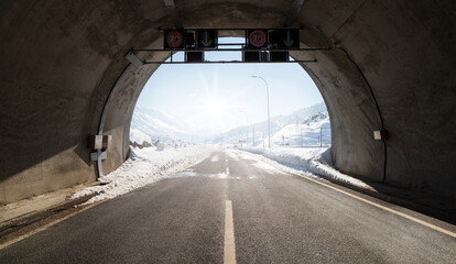 Tunnel road. Exit from the tunnel, snow on the asphalt road