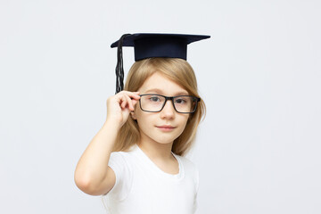 Portrait of a serious smart boy wearing suit and academic hat and glasses. Educational concept. Isolated over white.