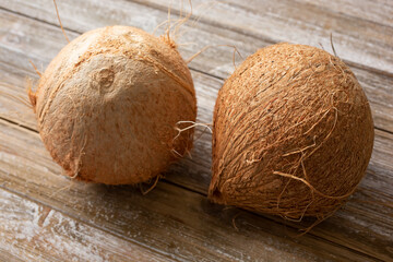 A view of two coconuts on a wooden table surface.
