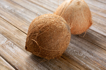 A view of two coconuts on a wood table surface.