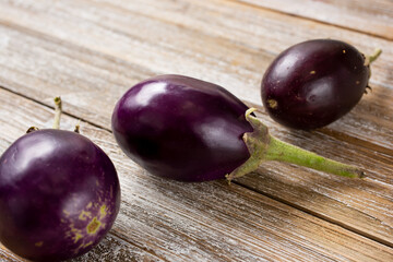 A view of three small Indian eggplants, on a rustic wood surface.