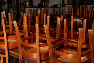 A view of a closed restaurant dining room, featuring all of the chairs turned over on the tables. 