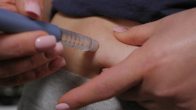 Close-up of a diabetic woman doing an injection of insulin in the stomach with an insulin pen.