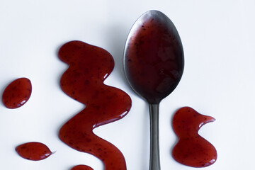 the drops of homemade sauce and a spoon on a white background