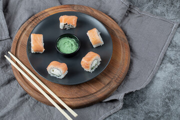 Salmon maki rolls in a white plate with wasabi sauce