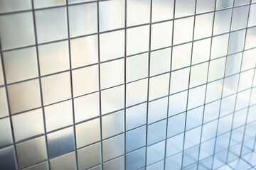 A closeup view of a background of metallic reflective silver tiles as a wall facade.