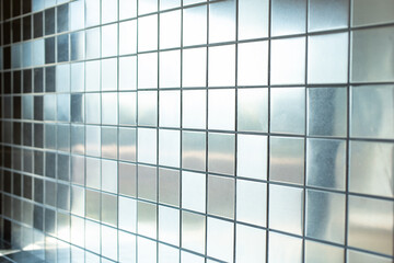 A closeup view of a background of metallic reflective silver tiles as a wall facade.