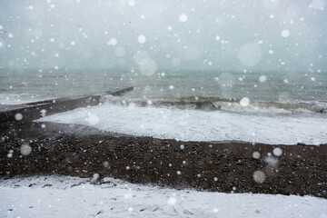 Beach on the Black Sea coast in winter. Sea waves and the snow, the strong snowstorm.