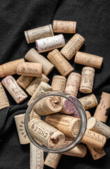 Bunch of wine corks and a glass over a black blanket
