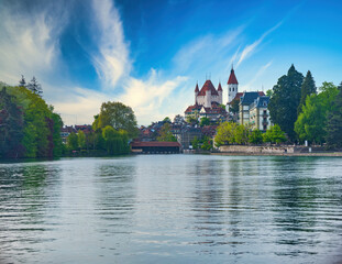 Thun town from Thun Lake. Castle and church towers, old buildings and wooden bridge across Aare river, Switzerland
