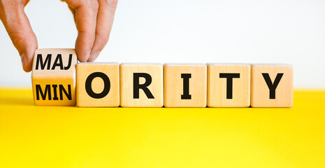 Minority or majority symbol. Businessman turns a cube and changes the word 'minority' to 'majority'. Beautiful yellow table, white background. Minority or majority and business concept. Copy space. - obrazy, fototapety, plakaty