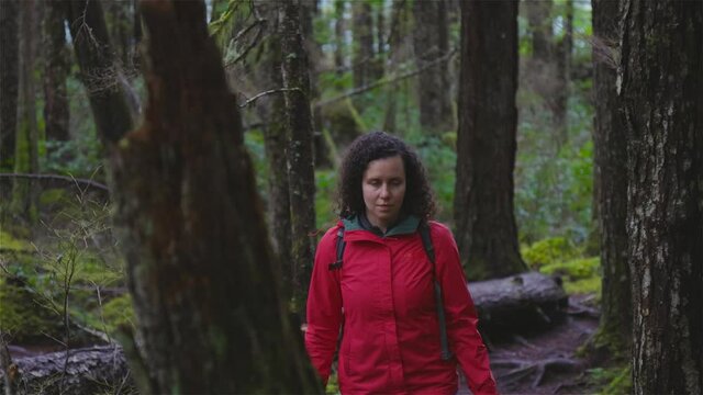 Girl Hiking on a Path in the Rain Forest during a rainy Winter Season. Squamish, North of Vancouver, British Columbia, Canada. Slow motion