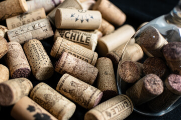 Bunch of wine corks and a glass over a black blanket
