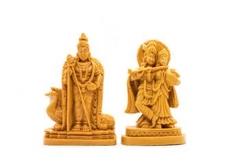 The hand-carved wooden idol of Lord Murugan with Radha Krishna is isolated on a white background