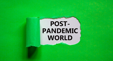 Post-pandemic world symbol. The words 'Post-pandemic world' appearing behind torn green paper. Beautiful green background, copy space. Medical and COVID-19 pandemic post-pandemic world concept.