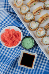 Hot sushi rolls on a white ceramic platter with sauces