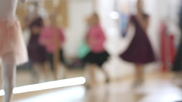 Unrecognizable Caucasian children running in circle passing camera. Group of active boys and girls exercising before ballet rehearsal in dancing school. Fitness and art concept.