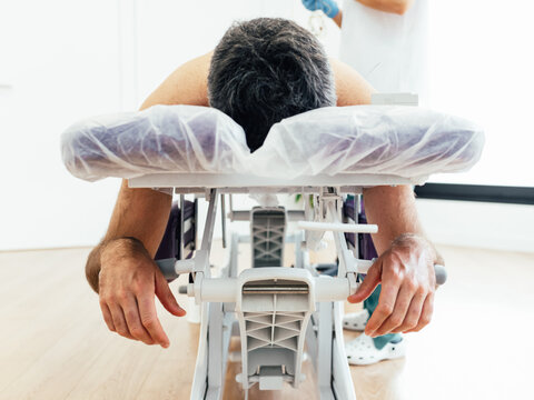 Patient Lying Face Down On A Stretcher In The Physiotherapy Clinic. Height Adjustable Medical Table