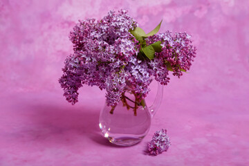 Fresh and  beautiful lilac bouquet in a glass vase on the pink background