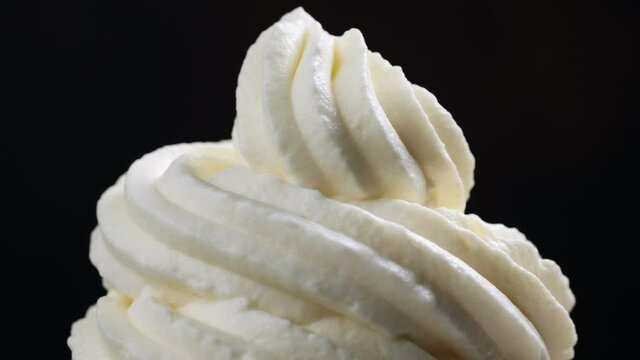 close up of rotating whipped cream on black background