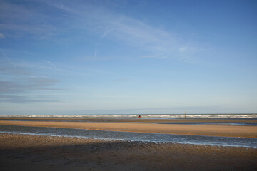 A person is riding a horse by the Flemish coastline, the beach of the North Sea is completely abandoned