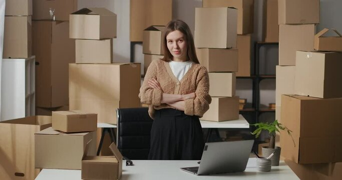 successful businesswoman in room of apartment using as warehouse for boxes with goods for business