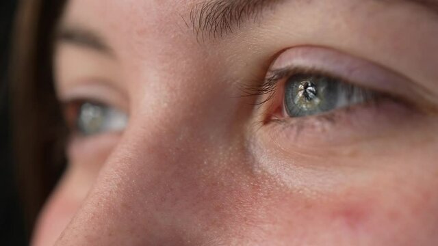 Smiling closeup profile of woman face opening grey blue eyes with happy smile in slow motion.