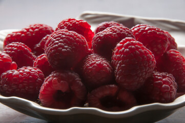 Red raspberries backlit in a scallop shell dish