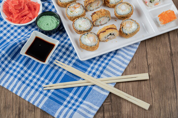 Fototapeta na wymiar Fried hot rolls in a wooden platter with soy sauce, wasabi and ginger