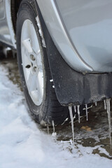 Stalactites hang from the fender of a car.