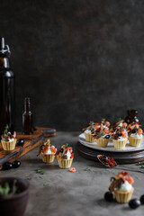 Canapes with curd cheese and seafood on a wooden board. Small snacks on a dark background.
