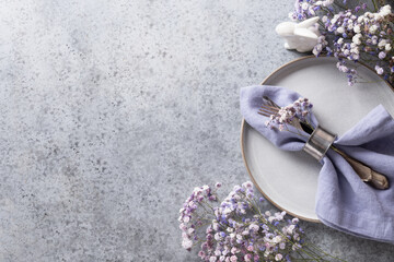 Easter violet table setting with bunny and festive decor on grey table. Top view. Space for text.
