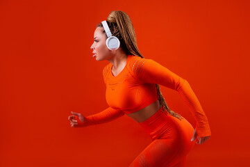 beautiful adult woman in a tracksuit on a red background in headphones 