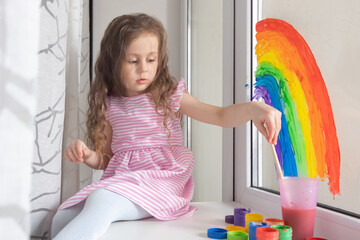 child at home draws a rainbow on the window. Flash mob society community on self-isolation quarantine pandemic coronavirus. Children create artist paints creativity vacation