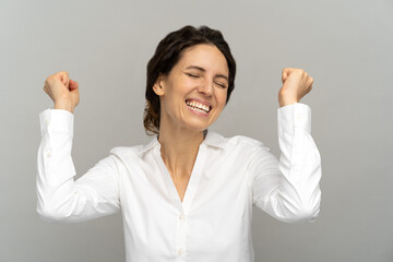 Cheerful winning successful office worker or businesswoman raising fists celebrates career ladder...