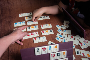 Kid playing Rummy with game tiles laid on a plastic rack simulating wood, in a mosaic style 