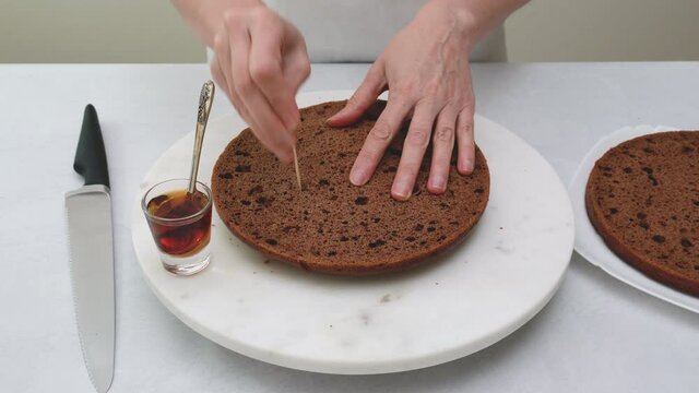 Chocolate cake recipe. Chef using toothpicks to poke holes all over the cake