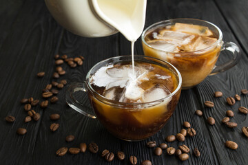 Iced coffee with milk in the glass cups  on the black wooden  background