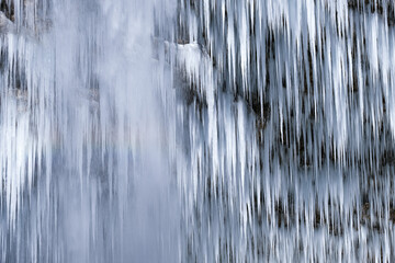Beautiful long icicles of a frozen waterfall, with water flowing and crashing down and Ice water...