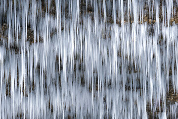 Beautiful long icicles of a frozen waterfall, with water flowing and crashing down and Ice water...
