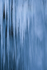 Beautiful long icicles of a frozen waterfall, with water flowing and crashing down and Ice water dripping from the tips of icicles in a cold eery and moody atmosphere in a cave in the mountains 
