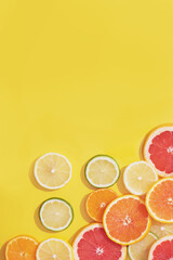 Flat lay made of different citrus fruits slices on yellow background.