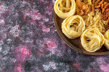 Plate of various macaroni on colorful background