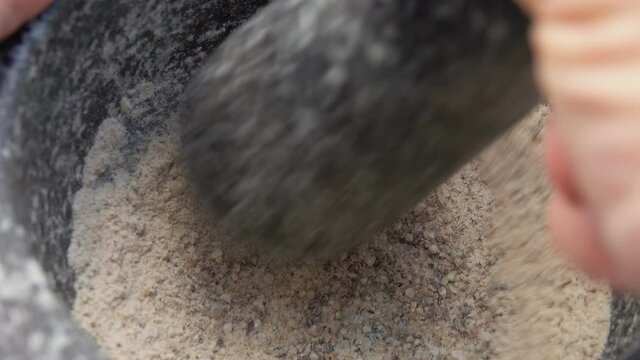 Super close-up of stone pestle mixing spices in the grey stone mortar