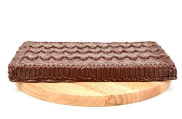 Chocolate waffle cake lying on a wooden cutting board and isolated on a white background