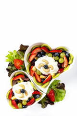 Fruchtsalat in zwei Herzschalen serviert, von beiden Seiten mit dem Salat dekoriert. 