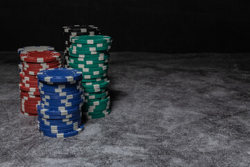 poker chips grouped in towers on the left of the image, with blue chips in front followed by green and red ones, black and white in the background with lots of empty space on the right